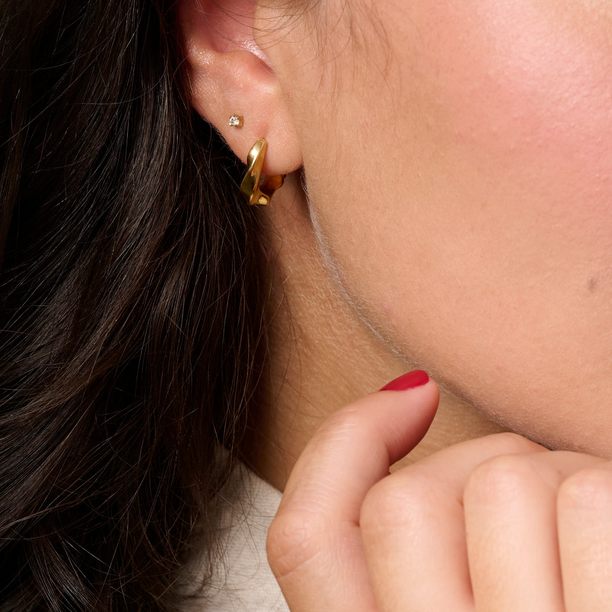 Close-up of a person's ear wearing a gold huggie twisted hoop earring and a small diamond stud earring.

Gros plan sur l'oreille d'une personne portant une boucle d'oreille anneau dorée torsadée et un petit clou serti d'une pierre.