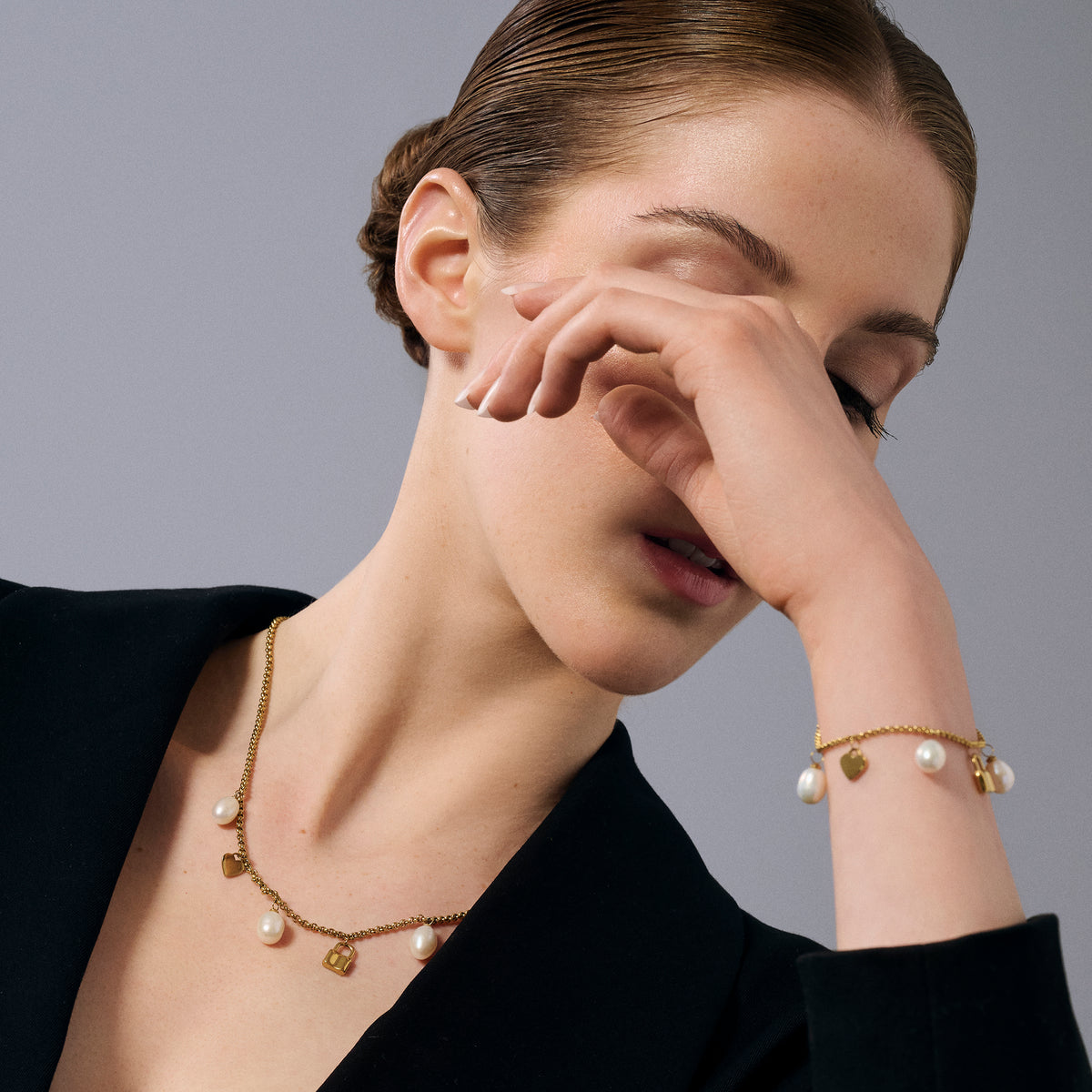 Gold stainless steel charm necklace and bracelet with freshwater pearls, heart charm and lock pendant, elegant modern jewelry set, hypoallergenic non-tarnish durable everyday jewelry.
